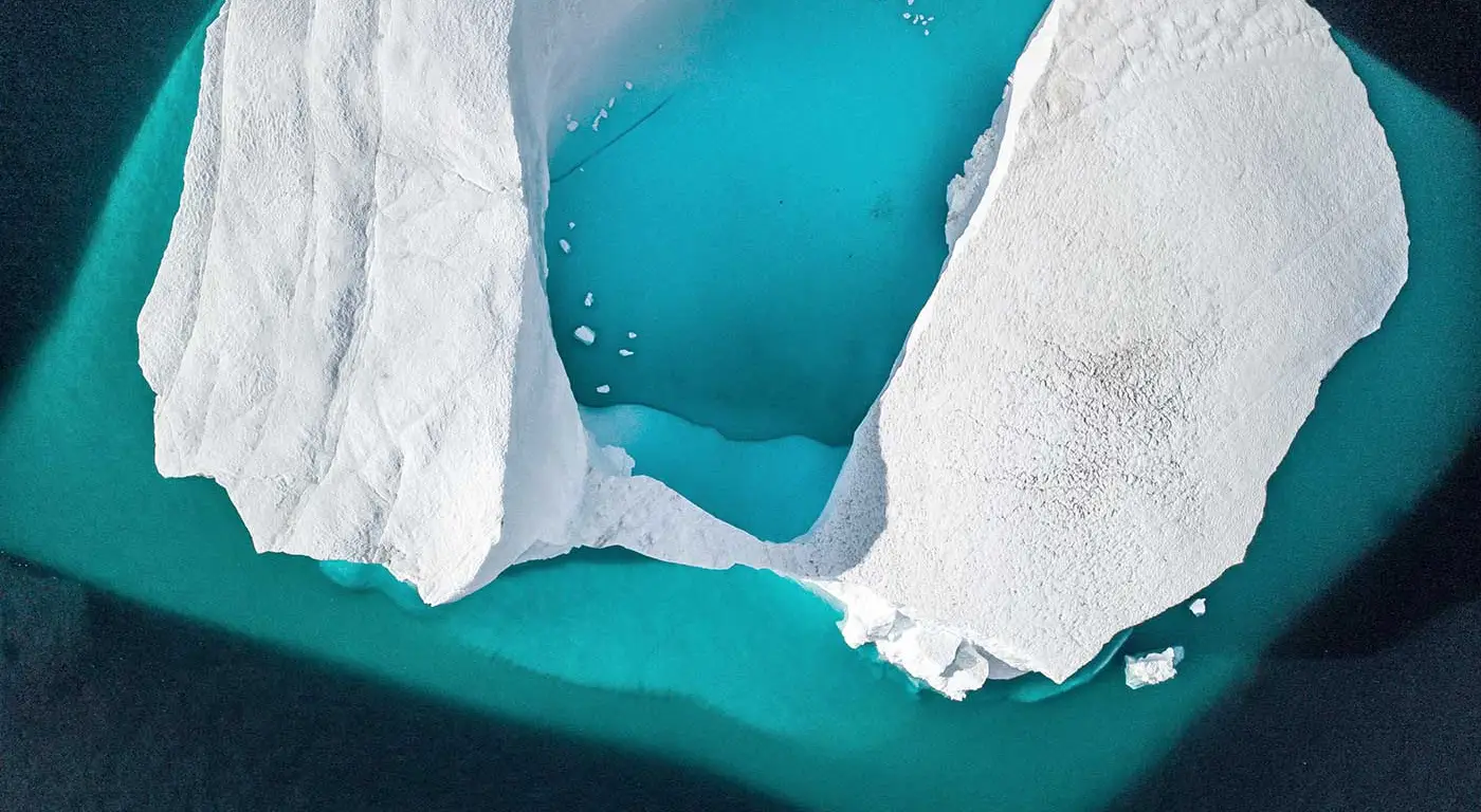 An iceberg in a vivid blue ocean, from above